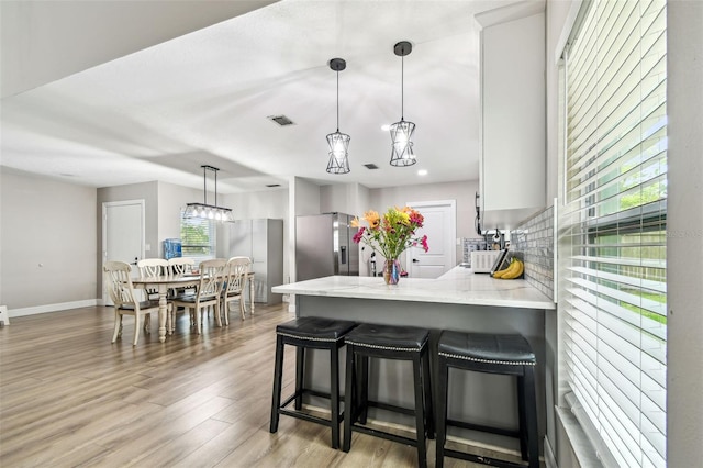 509 Stone Dr, Brandon, FL 33510 - kitchen featuring stainless steel fridge with ice dispenser, healthy amount of natural light, a peninsula, light wood-type flooring, and recessed lighting