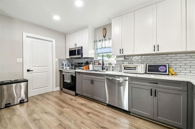 509 Stone Dr, Brandon, FL 33510 - kitchen with stainless steel appliances, gray cabinets, a sink, decorative backsplash, and light wood-style floors