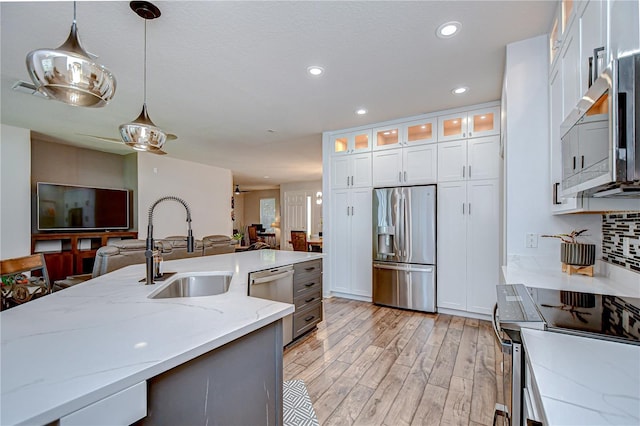 445 Arch Ridge Loop, Seffner, FL 33584 - kitchen featuring stainless steel appliances, a sink, open floor plan, hanging light fixtures, and light wood finished floors