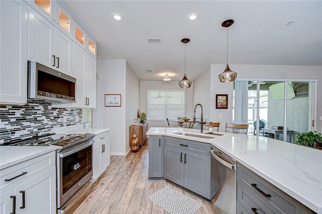 445 Arch Ridge Loop, Seffner, FL 33584 - kitchen featuring appliances with stainless steel finishes, a sink, gray cabinetry, baseboards, and light wood-style floors