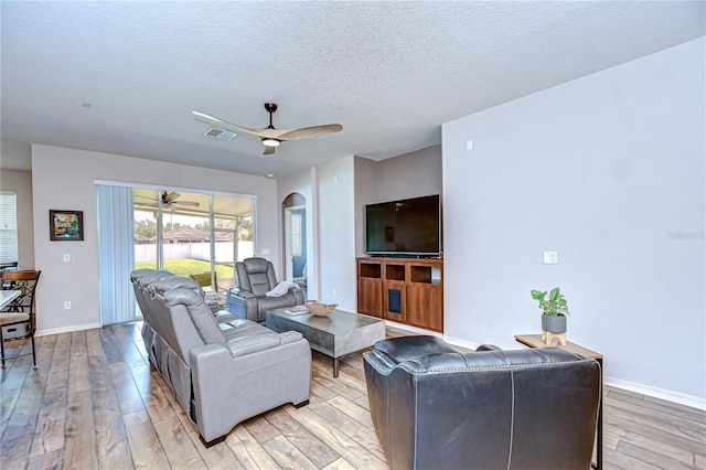 445 Arch Ridge Loop, Seffner, FL 33584 - living room featuring light wood-style flooring, arched walkways, a ceiling fan, a textured ceiling, and baseboards