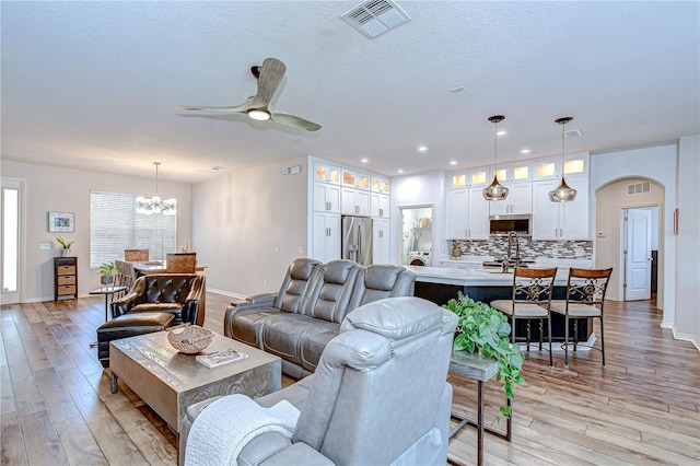 445 Arch Ridge Loop, Seffner, FL 33584 - living area with arched walkways, light wood finished floors, a chandelier, a ceiling fan, and recessed lighting