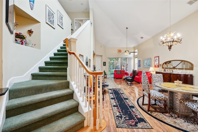 7246 Gaberia Rd, New Port Richey, FL 34655 - stairs featuring wood finished floors, high vaulted ceiling, a chandelier, and ceiling fan