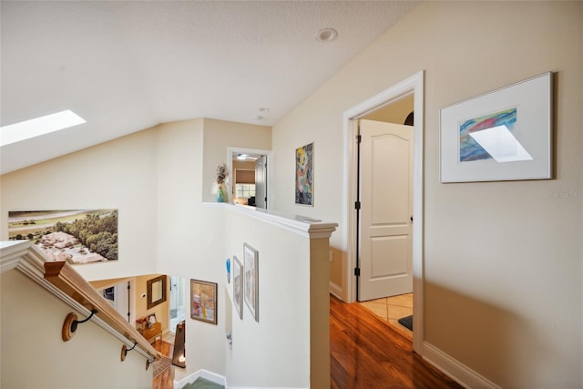 7246 Gaberia Rd, New Port Richey, FL 34655 - corridor with a skylight, wood finished floors, baseboards, an upstairs landing, and vaulted ceiling