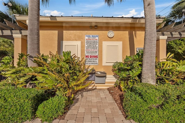 7246 Gaberia Rd, New Port Richey, FL 34655 - view of exterior entry with stucco siding and a pergola