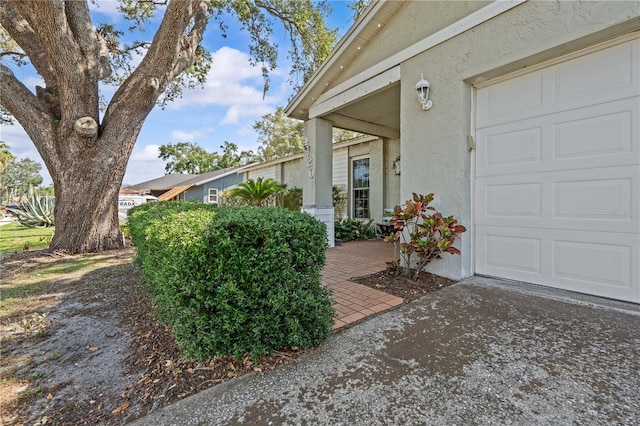 view of side of property with stucco siding, an attached garage, and concrete driveway