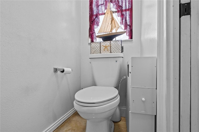bathroom featuring baseboards and toilet