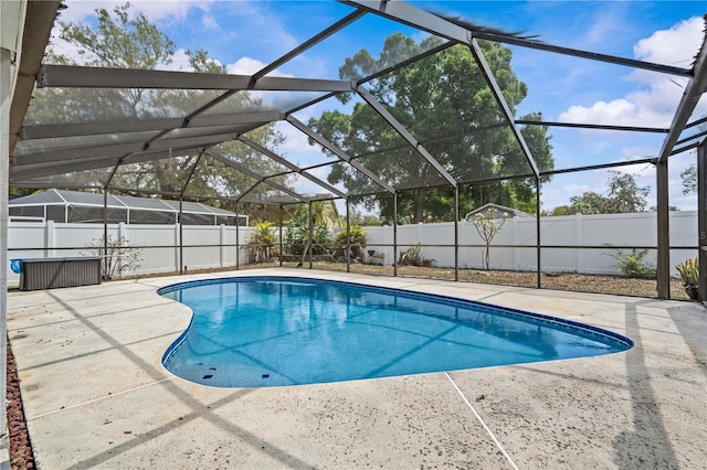 view of swimming pool with a fenced backyard, a patio area, and glass enclosure