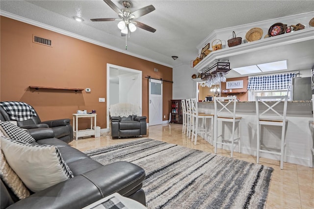 tiled living room with a barn door, ornamental molding, a textured ceiling, and a ceiling fan