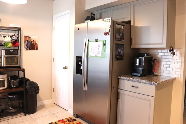 1048 Winding Water Way, Clermont, FL 34714 - kitchen with stainless steel fridge, light stone counters, light tile patterned floors, decorative backsplash, and baseboards