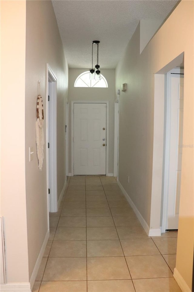 1048 Winding Water Way, Clermont, FL 34714 - hall with light tile patterned floors, a textured ceiling, a chandelier, and baseboards
