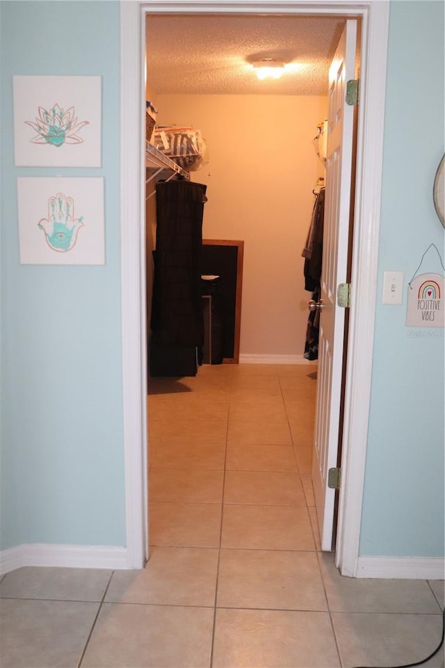 1048 Winding Water Way, Clermont, FL 34714 - hallway with light tile patterned floors, a textured ceiling, and baseboards