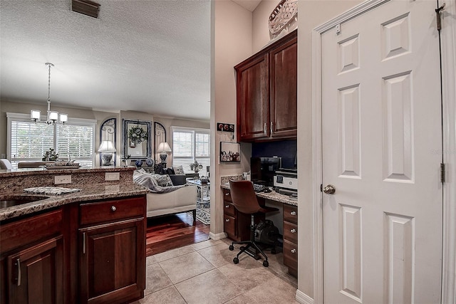 kitchen with healthy amount of natural light, open floor plan, a textured ceiling, dark stone counters, and light tile patterned flooring