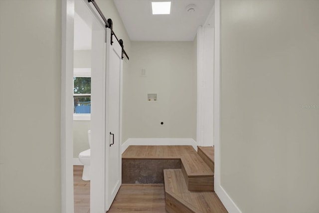 1352 Parkwood St, Clearwater, FL 33755 - hallway with a barn door, light wood finished floors, and baseboards
