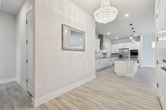 8421 Ivy Stark Blvd, Wesley Chapel, FL 33545 - kitchen with stainless steel appliances, a chandelier, wall chimney exhaust hood, light wood-style flooring, and baseboards