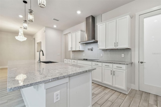 8421 Ivy Stark Blvd, Wesley Chapel, FL 33545 - kitchen with wall chimney range hood, a sink, white cabinetry, light wood-type flooring, and decorative backsplash