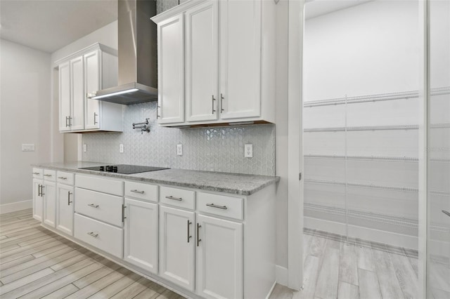 8421 Ivy Stark Blvd, Wesley Chapel, FL 33545 - kitchen with wall chimney exhaust hood, black electric stovetop, light wood-style flooring, and baseboards