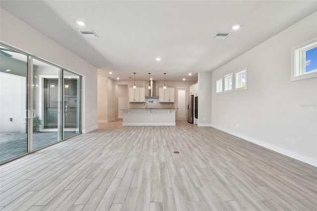 8421 Ivy Stark Blvd, Wesley Chapel, FL 33545 - unfurnished living room with light wood-style floors, baseboards, recessed lighting, and a sink