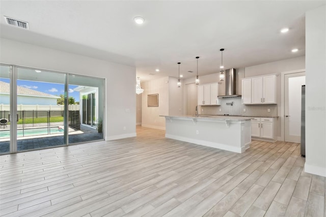 8421 Ivy Stark Blvd, Wesley Chapel, FL 33545 - kitchen featuring wall chimney exhaust hood, fridge, light wood-type flooring, a breakfast bar, and recessed lighting