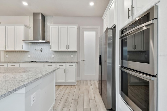 8421 Ivy Stark Blvd, Wesley Chapel, FL 33545 - kitchen with wall chimney exhaust hood, stainless steel appliances, white cabinets, light wood-style flooring, and decorative backsplash