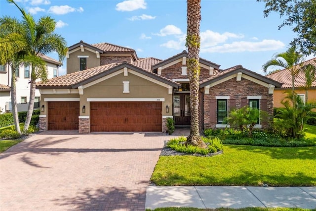 1416 Via Verdi Dr, Palm Harbor, FL 34683 - view of front facade featuring stone siding, stucco siding, a front yard, decorative driveway, and an attached garage