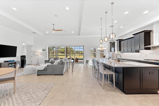 1416 Via Verdi Dr, Palm Harbor, FL 34683 - kitchen with light countertops, a tray ceiling, a chandelier, backsplash, and open floor plan