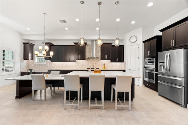 1416 Via Verdi Dr, Palm Harbor, FL 34683 - kitchen featuring appliances with stainless steel finishes, wall chimney range hood, decorative backsplash, an island with sink, and recessed lighting