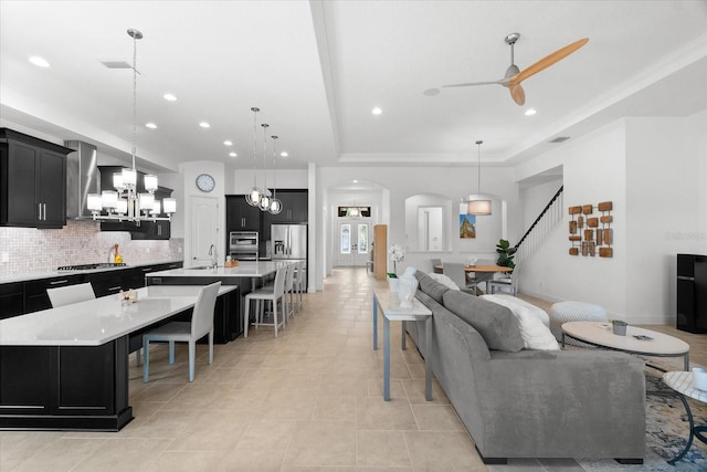 1416 Via Verdi Dr, Palm Harbor, FL 34683 - living room with ceiling fan, a tray ceiling, a chandelier, arched walkways, and recessed lighting