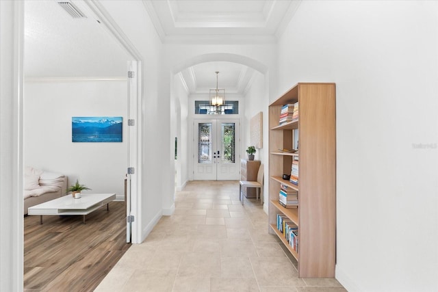 1416 Via Verdi Dr, Palm Harbor, FL 34683 - foyer featuring arched walkways, a tray ceiling, crown molding, a chandelier, and french doors