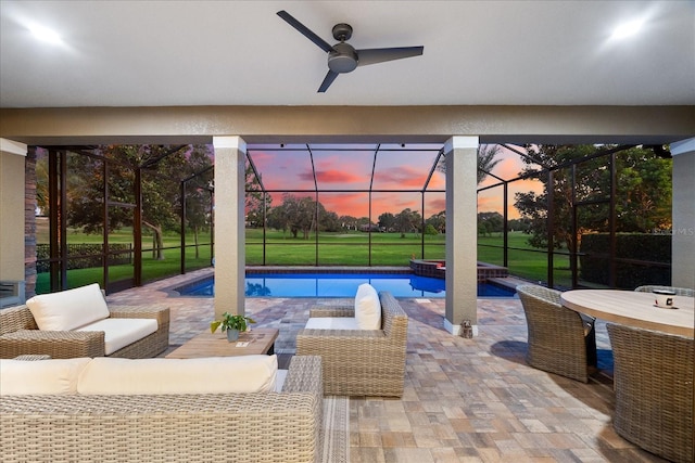 1416 Via Verdi Dr, Palm Harbor, FL 34683 - pool at dusk featuring an outdoor hangout area, a patio area, glass enclosure, and ceiling fan