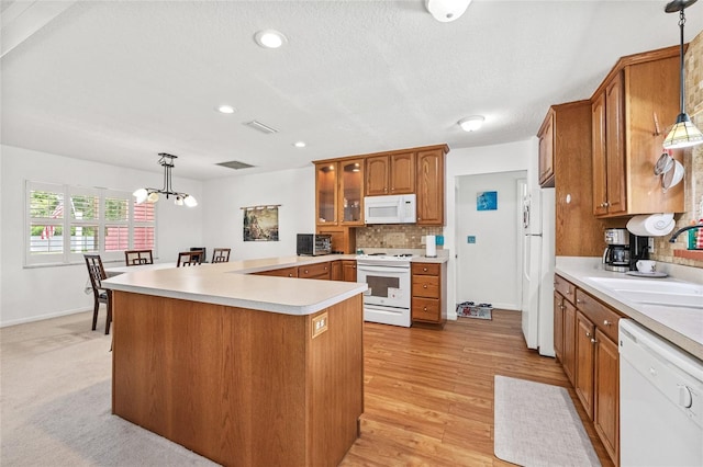 603 Royal Crest Dr, Brandon, FL 33511 - kitchen with white appliances, a sink, tasteful backsplash, brown cabinetry, and a peninsula