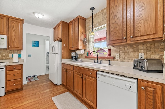 603 Royal Crest Dr, Brandon, FL 33511 - kitchen with white appliances, a sink, brown cabinetry, backsplash, and light countertops