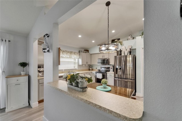 10449 Hunters Haven Blvd, Riverview, FL 33578 - kitchen with stainless steel appliances, lofted ceiling, light countertops, light wood-style floors, and decorative light fixtures
