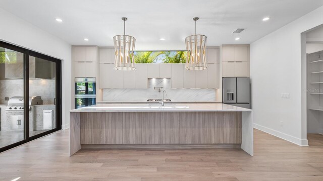 910 W Virginia Ave, Tampa, FL 33603 - kitchen featuring stainless steel appliances, modern cabinets, light countertops, tasteful backsplash, and a spacious island