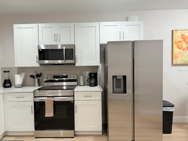 17099 Carleen Ave, Port Charlotte, FL 33948 - kitchen with appliances with stainless steel finishes, decorative backsplash, white cabinetry, light countertops, and light wood-type flooring