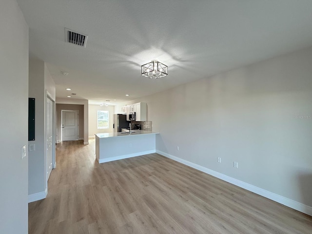 17099 Carleen Ave, Port Charlotte, FL 33948 - unfurnished living room with light wood finished floors, baseboards, recessed lighting, and a sink