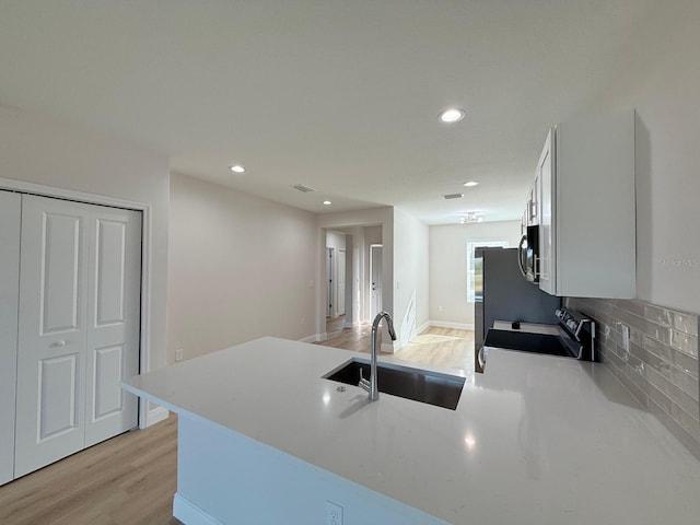 17099 Carleen Ave, Port Charlotte, FL 33948 - kitchen with range, a peninsula, a sink, light wood finished floors, and stainless steel microwave