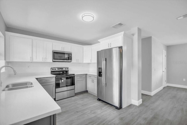 2711 E 22nd Ave, Tampa, FL 33605 - kitchen with stainless steel appliances, a sink, light wood-style floors, and baseboards