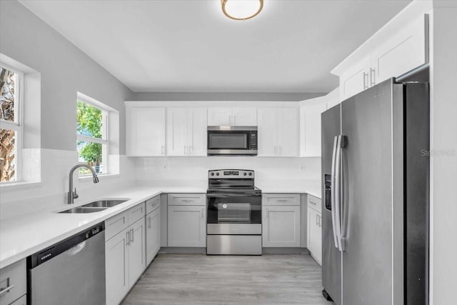 2711 E 22nd Ave, Tampa, FL 33605 - kitchen with appliances with stainless steel finishes, a sink, light wood-style flooring, light countertops, and white cabinetry