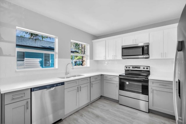 2711 E 22nd Ave, Tampa, FL 33605 - kitchen featuring stainless steel appliances, a sink, gray cabinets, light wood finished floors, and light countertops
