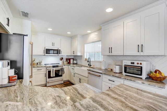 11121 Running Pine Dr, Riverview, FL 33569 - kitchen featuring gas stove, dishwasher, a sink, light stone counters, and white cabinetry