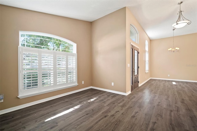 unfurnished room with dark wood finished floors, a chandelier, and baseboards