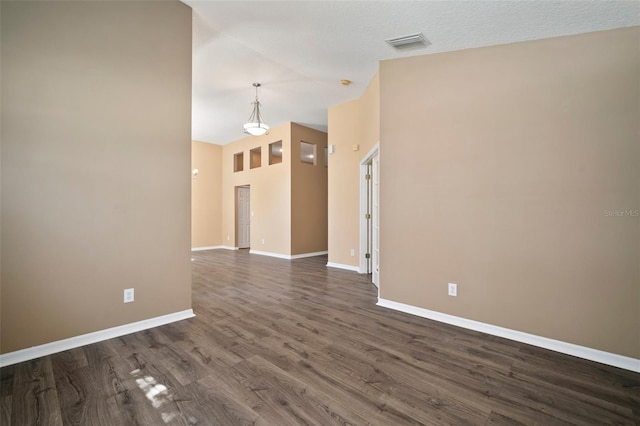 unfurnished room featuring baseboards, dark wood-style floors, and vaulted ceiling