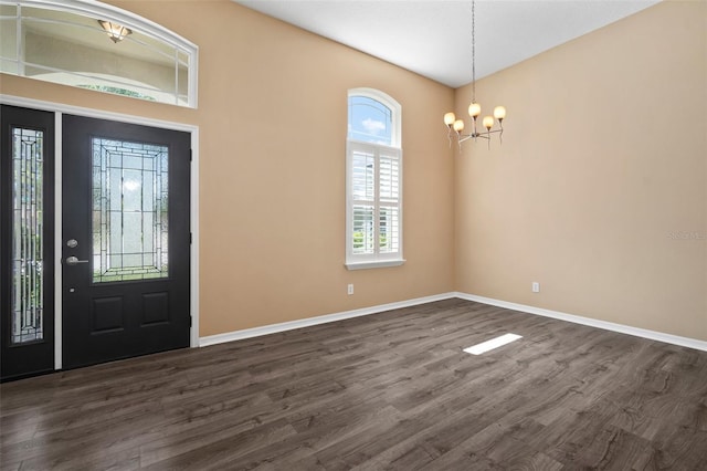 foyer entrance featuring a chandelier, dark wood finished floors, and baseboards