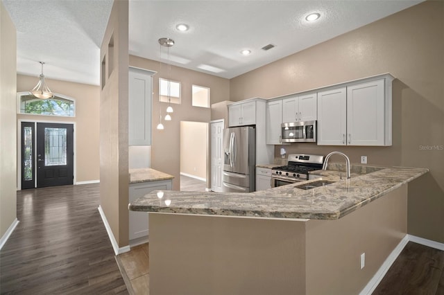 kitchen featuring appliances with stainless steel finishes, baseboards, wood finished floors, recessed lighting, and a textured ceiling
