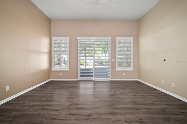 empty room with dark wood-type flooring and baseboards