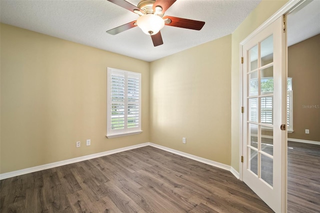 spare room with dark wood-style flooring, baseboards, a ceiling fan, and a textured ceiling