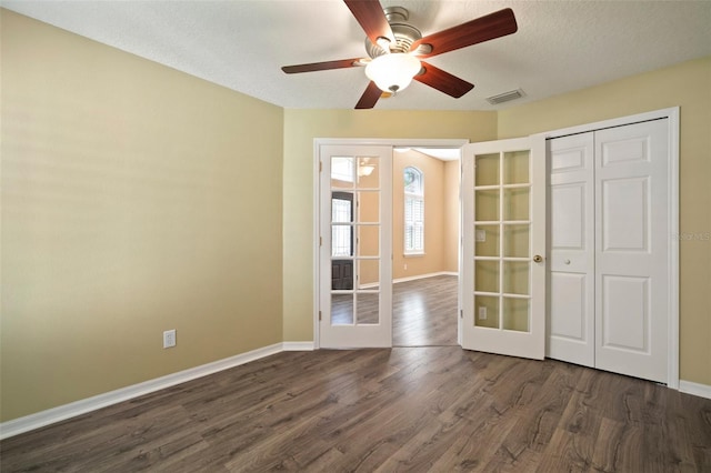unfurnished bedroom featuring french doors, dark wood-style flooring, baseboards, and a textured ceiling