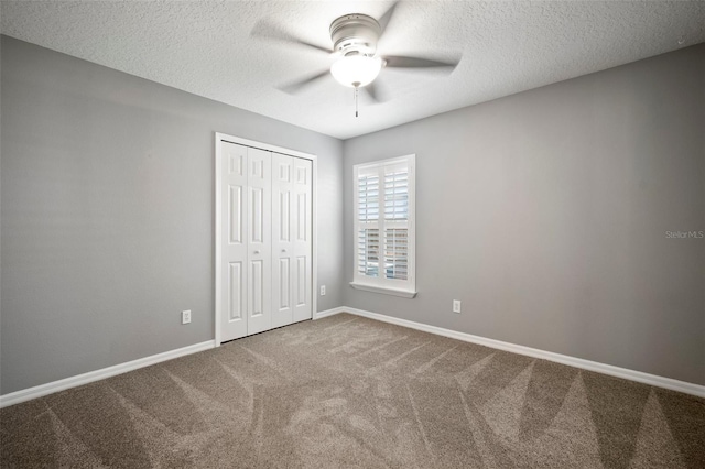 unfurnished bedroom featuring carpet flooring, baseboards, a closet, a textured ceiling, and a ceiling fan