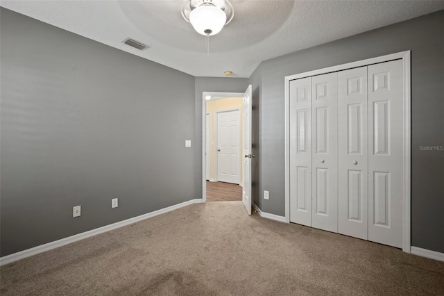 unfurnished bedroom with carpet floors, baseboards, a closet, and a ceiling fan